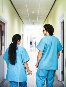 Des medcins en blouse bleue dans un couloir d'hôpital